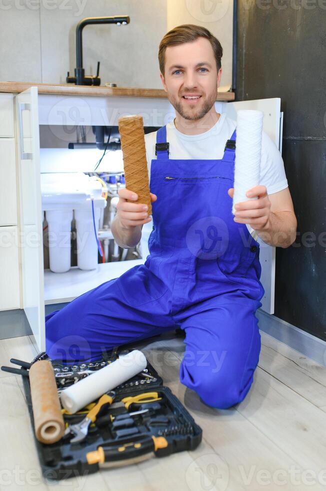 Young plumber or technician installing or repairing system of water filtration photo