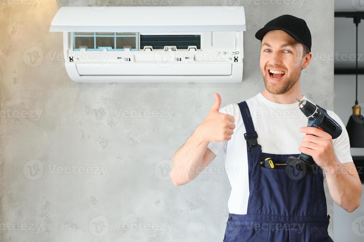 Smiling young male electrician repair conditioner in client home. Man mechanic or repairman fix filters in air condition device at customer house photo