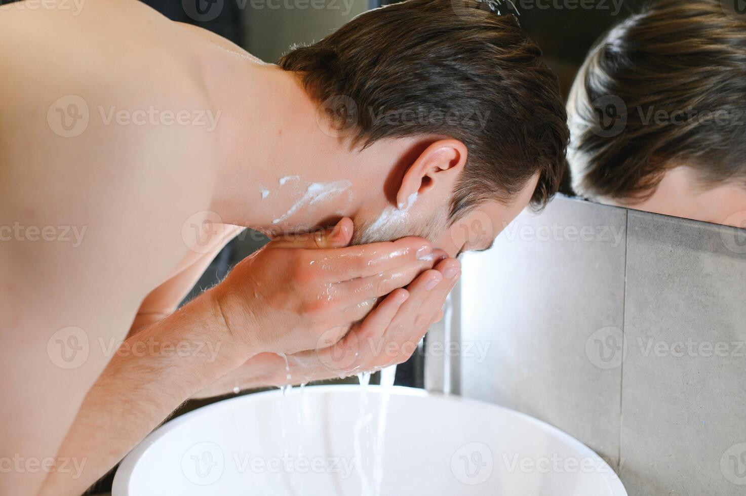 A man washes his face after shaving photo
