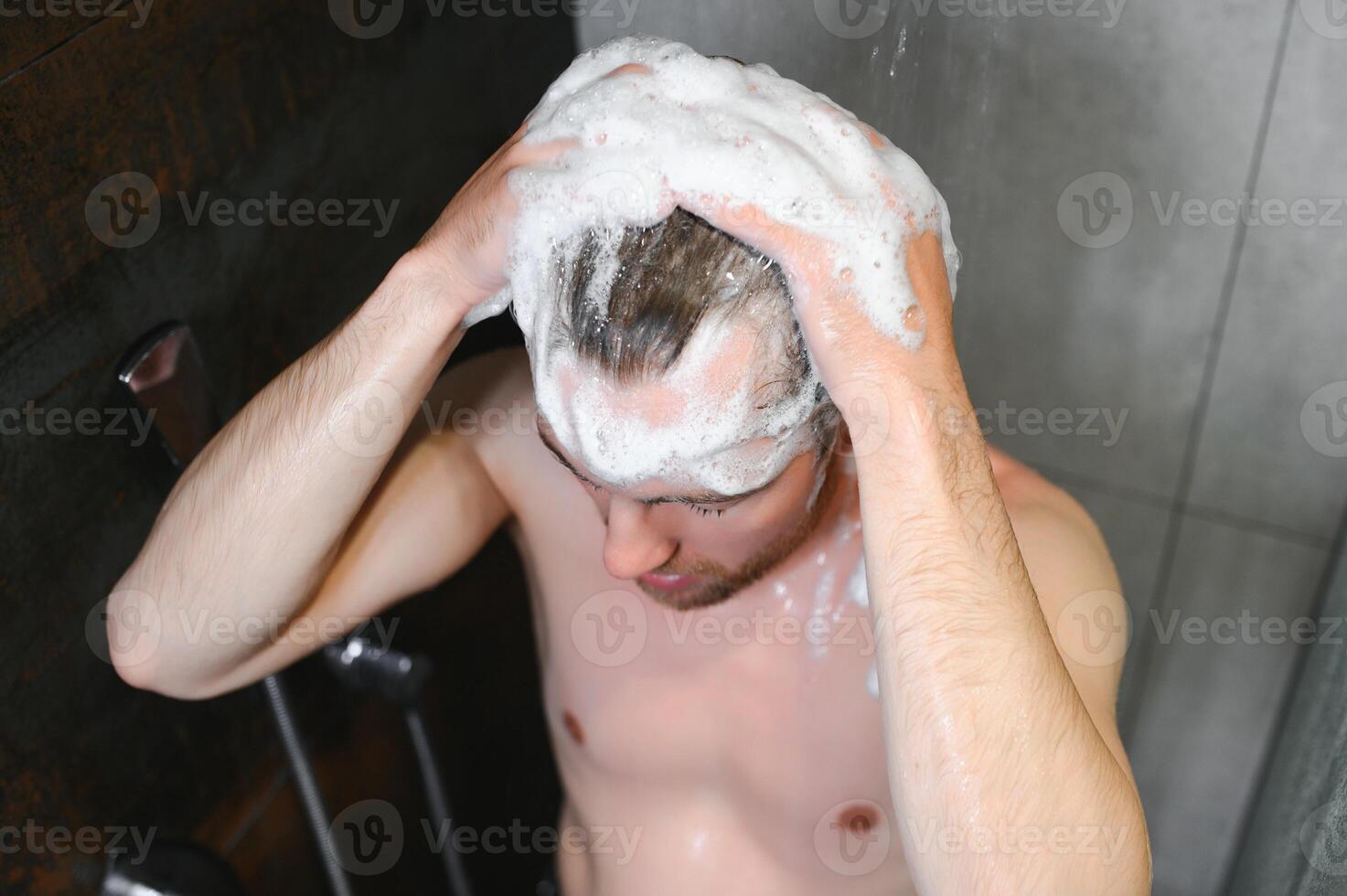 The man is washing his hair, he use shampoo. photo