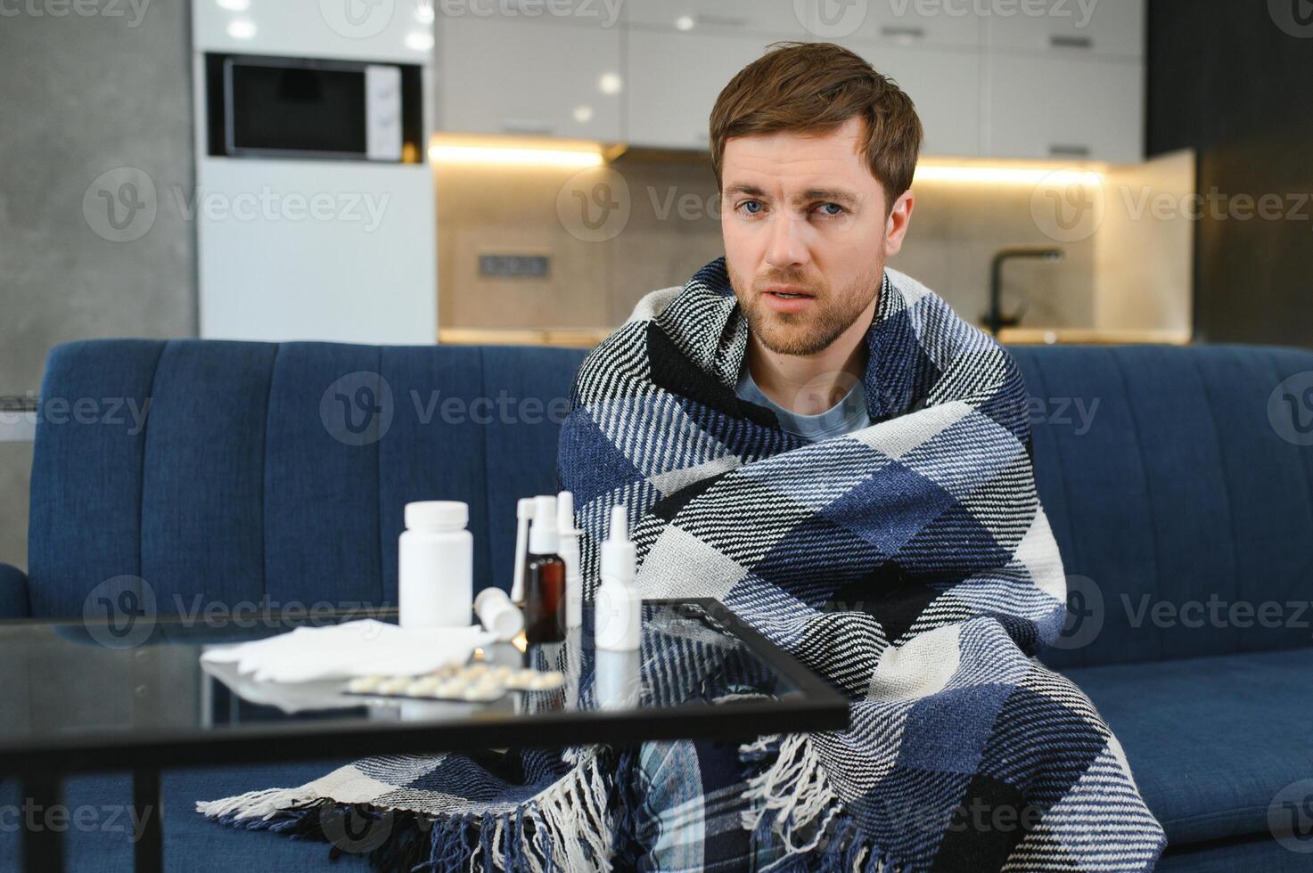 Sick man on sofa at home in living room. man feeling sick with cold and fever at home, ill with flu disease sitting on the sofa. It's the season of sneezes. photo