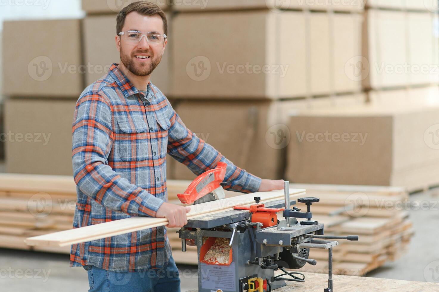 Wood cutting table with electric circular saw. Professional carpenter in uniform cutting wooden board at sawmill carpentry manufacturing . Sawing machine photo