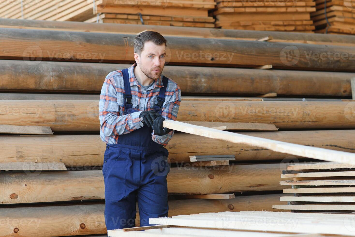 Carpenter in uniform check boards on sawmill photo