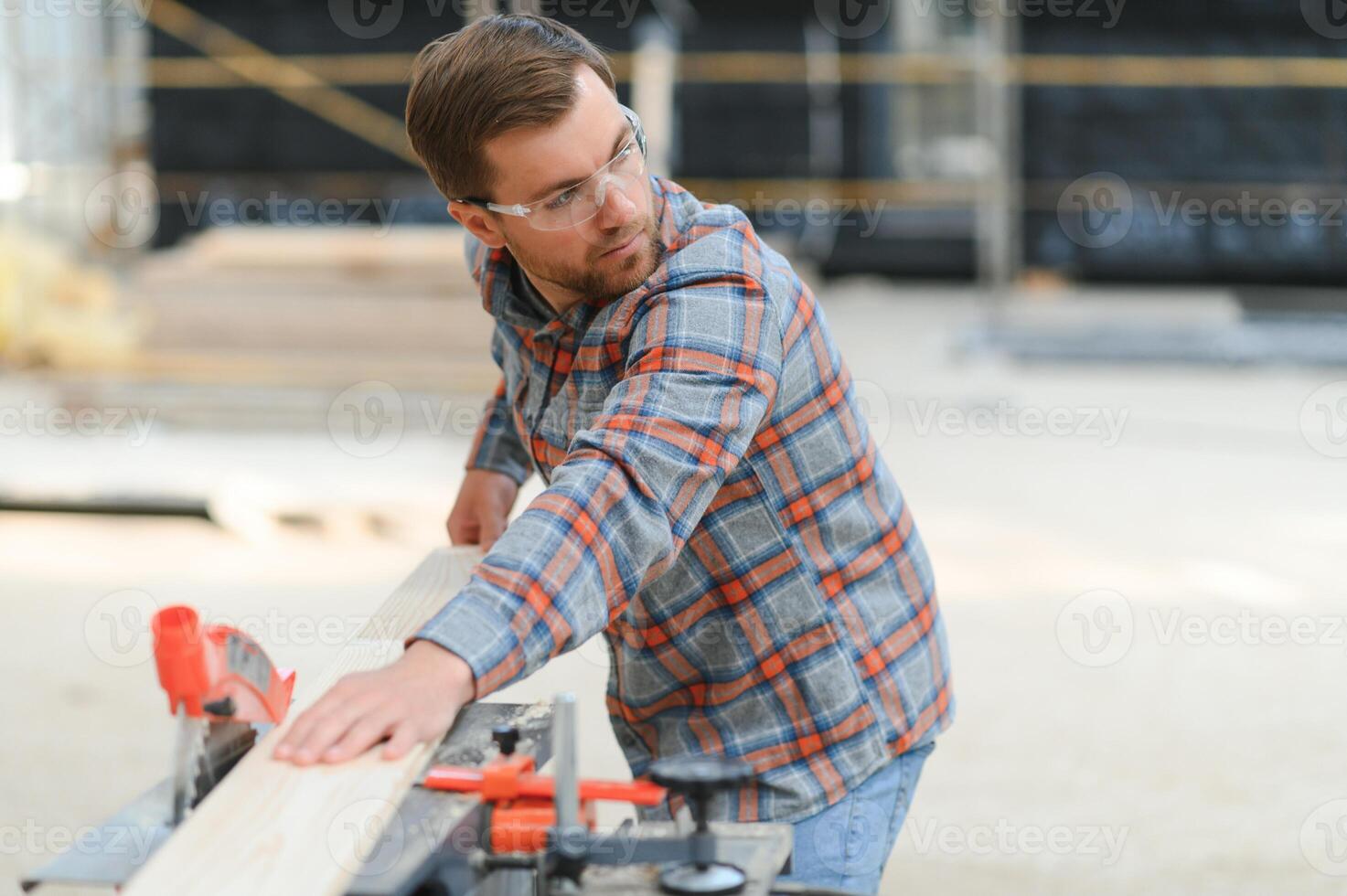 Closeup professional carpenter hold electric circular saw at sawmill. Skilled joiner using circular saw for cutting wood board at woodworking workshop. Furniture production factory. Man cabinet maker photo