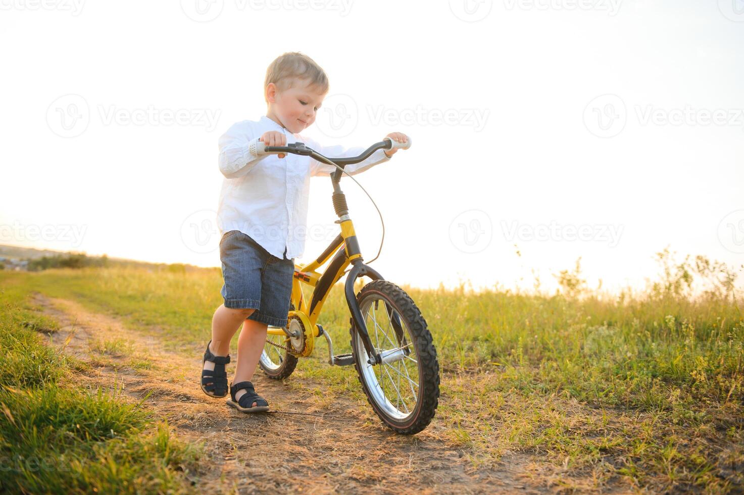 A handsome boy with bicycle in the summer field. photo