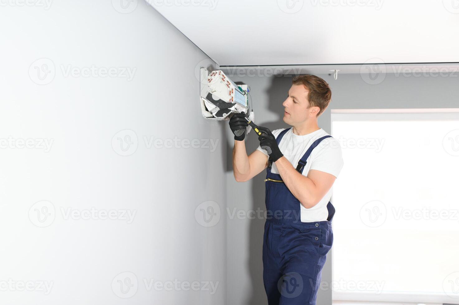handsome young man electrician installing air conditioning in a client house photo