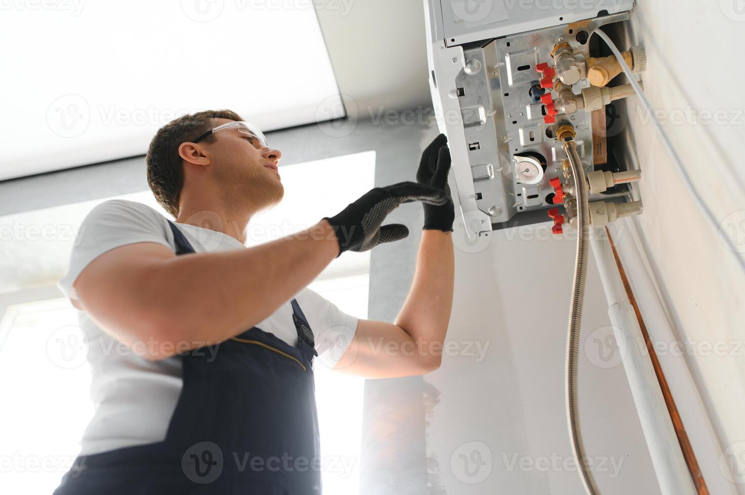 Gas engineer checking and cleaning a boiler during the inspection at home photo