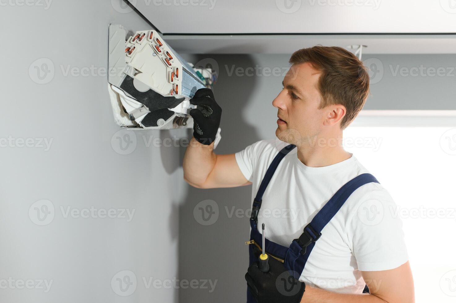 Male technician fixing air conditioner indoors photo