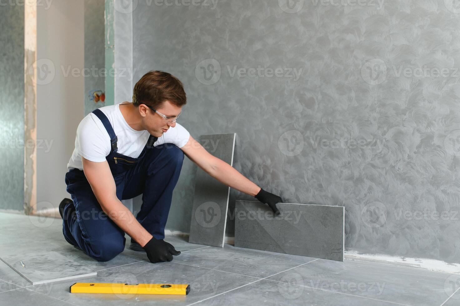 Worker installing ceramic tile on floor near wall. photo