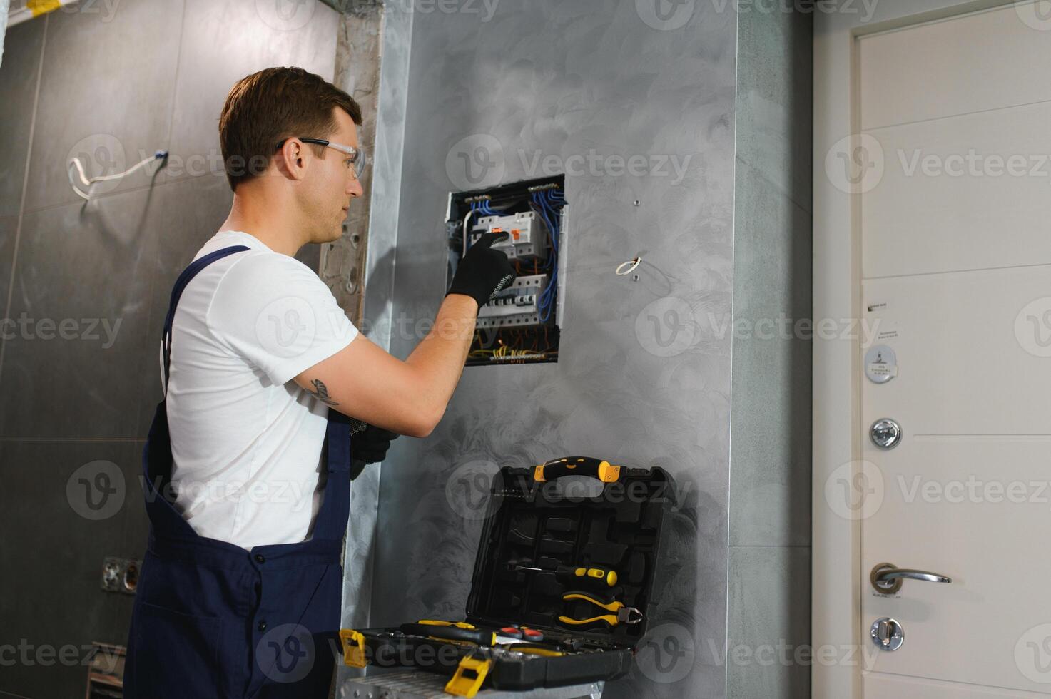 A male electrician works in a switchboard with an electrical connecting cable photo