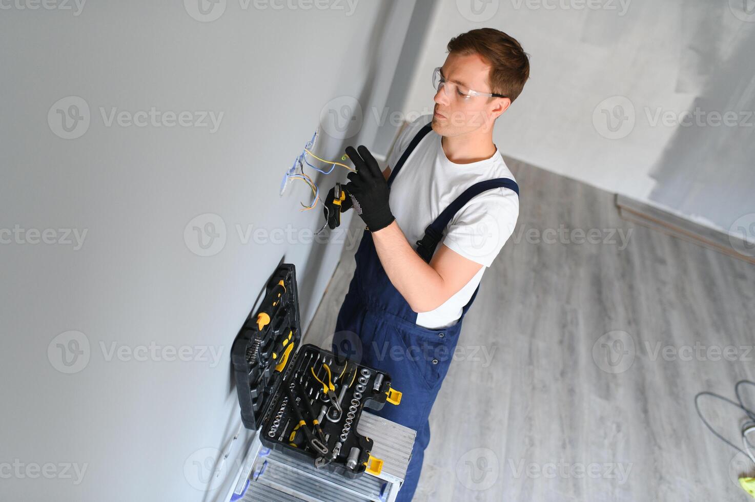 electricista con destornillador reparando poder enchufe en habitación foto
