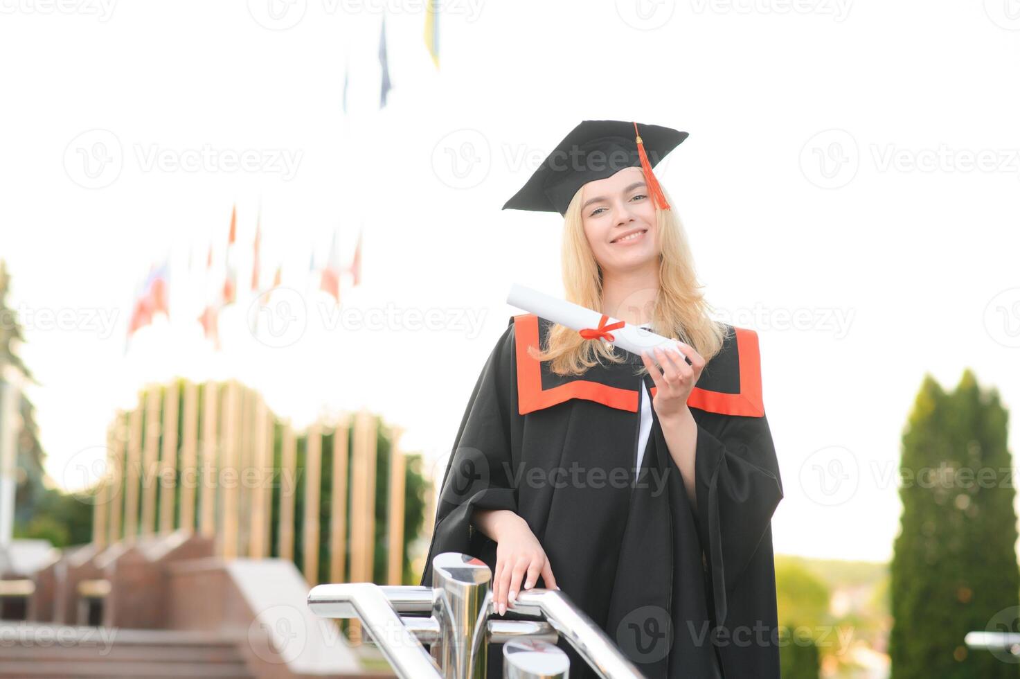 Happy university graduate girl. The girl is standing near the university against the background of the flags of different countries. The concept of international education. photo