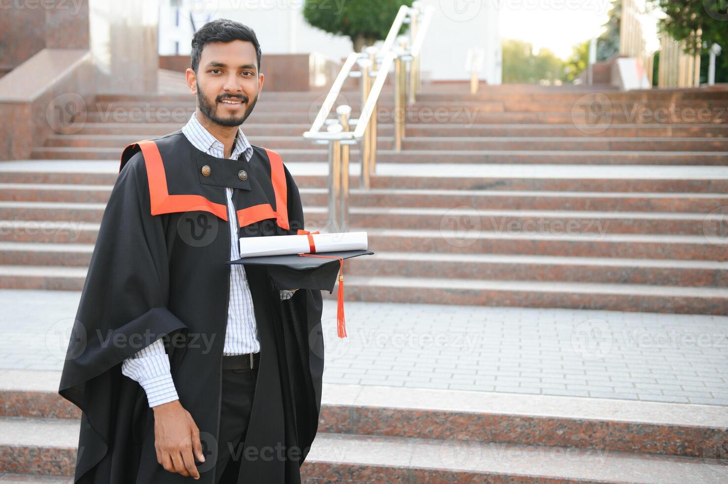 Handsome indian graduate in graduation glow with diploma. photo