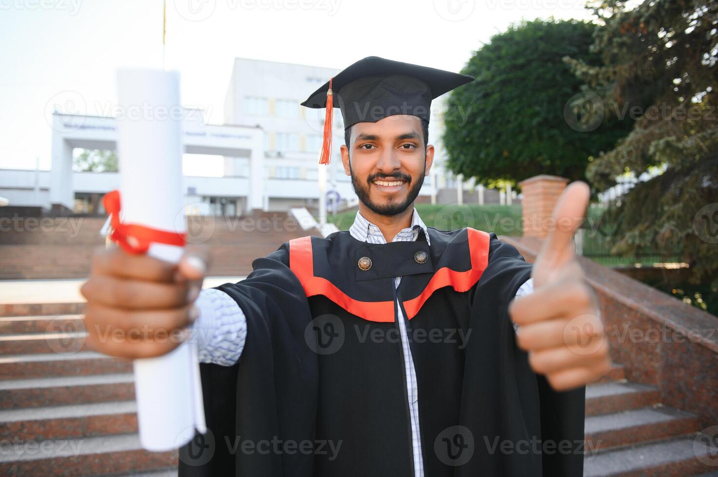 Handsome indian graduate in graduation glow with diploma. photo