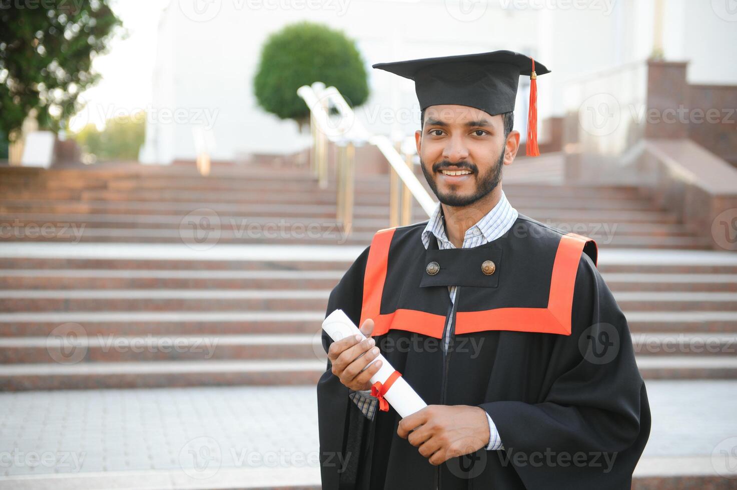 Portrait of indian handsome male graduate in graduation robe. photo