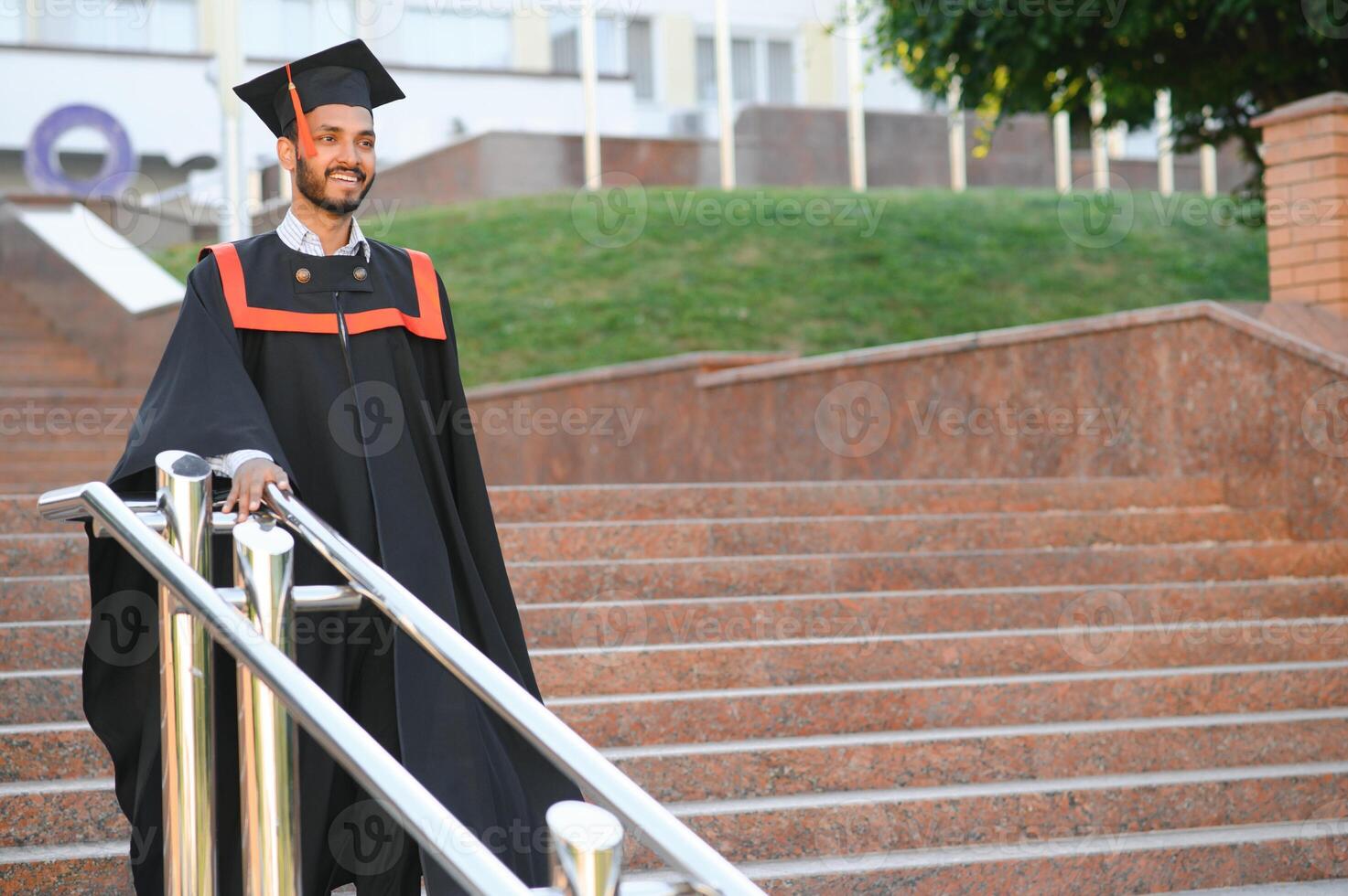 Portrait of indian handsome male graduate in graduation robe. photo