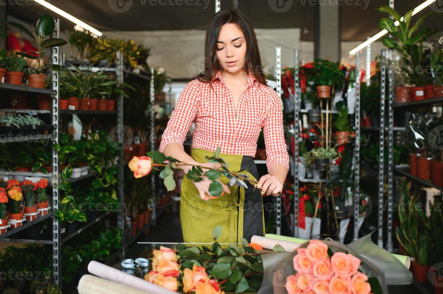 Young beautiful woman florist make bouquet of flowers at flower shop photo