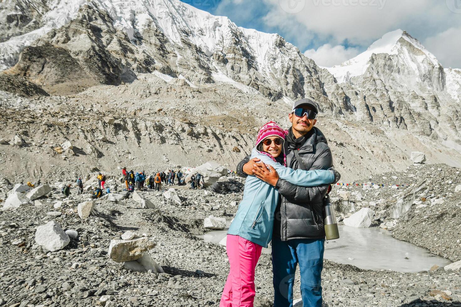 Young male guide and tourist woman on Everest base camp looking at camera hugs. Himalayas trekking EBC. Nepalese male guide leading tourist client in Sagarmatha national park official photo