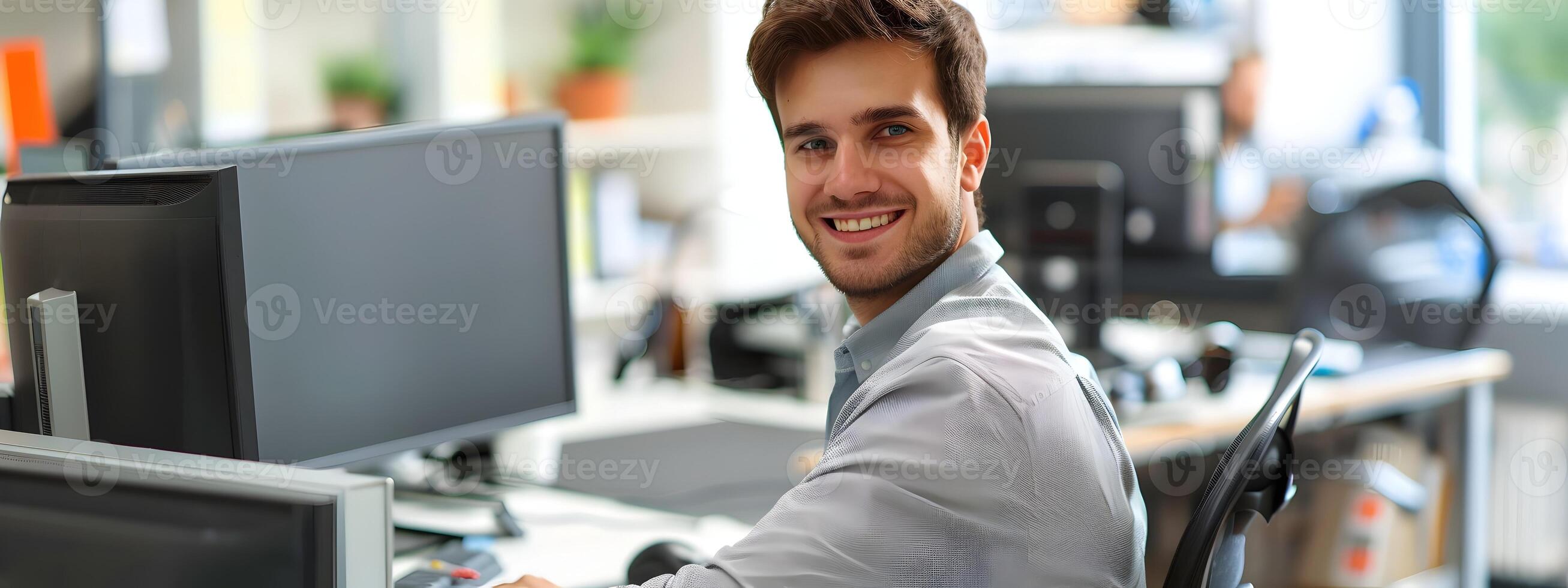Smiling Young Businessman Working at His Desk in a Bright Office Environment photo