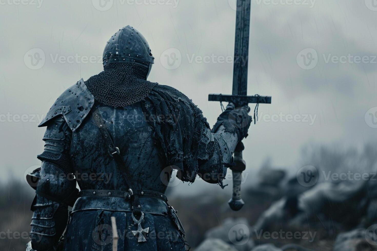 Armored medieval knight raises his sword amid a desolate battlefield, evoking bravery and solemn victory under a somber, overcast sky. Ideal for historical or fantasy-themed visuals photo
