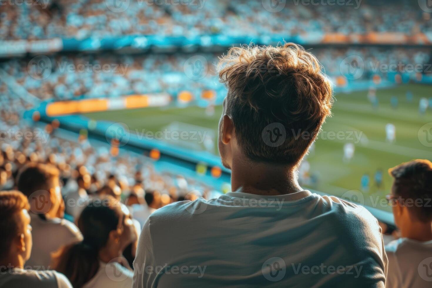 Young man watching football match at stadium with crowd cheering for favourite team photo