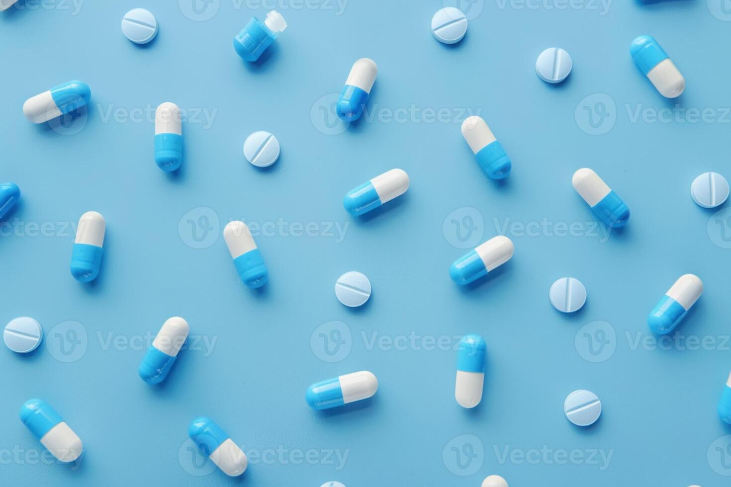 Overhead view of various pills and medicinal capsules scattered on a blue surface photo