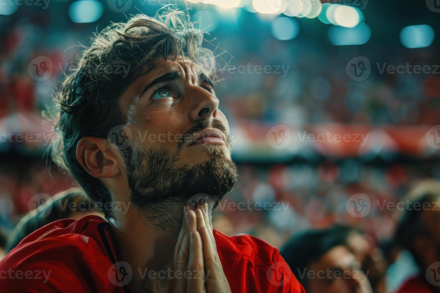 Young man praying with hope at football match in crowded stadium photo