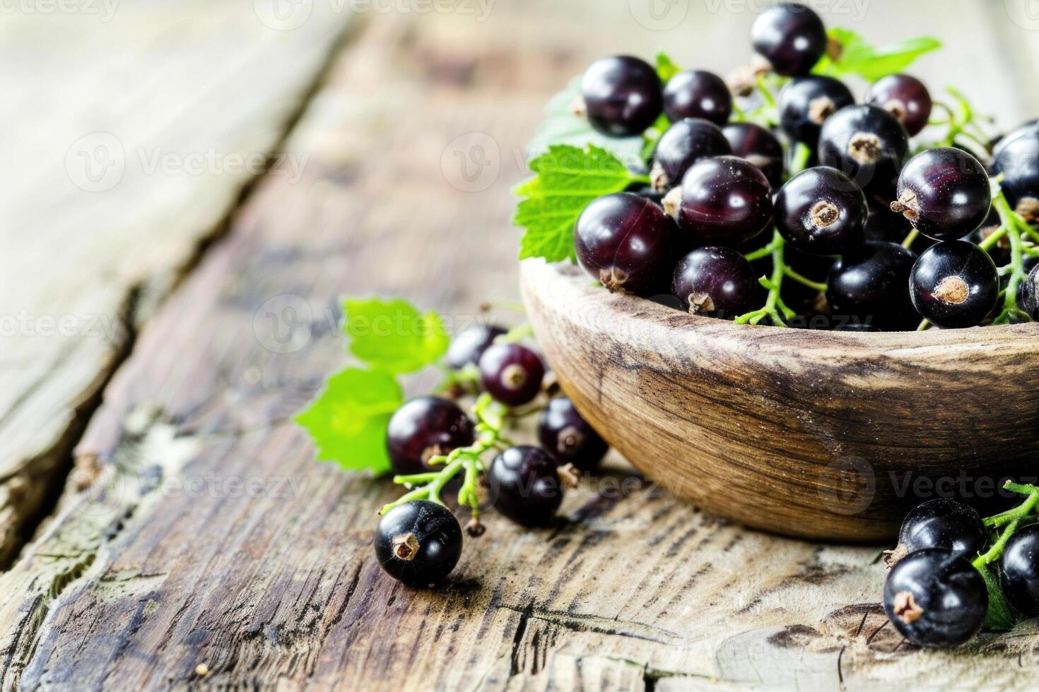 Freshly picked black currants overflowing in rustic wooden bowl on table photo