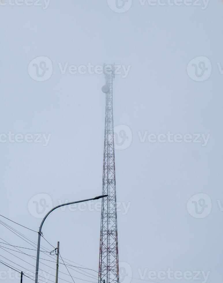 The tower base of the transceiver system towers high in the mountains with dense fog photo