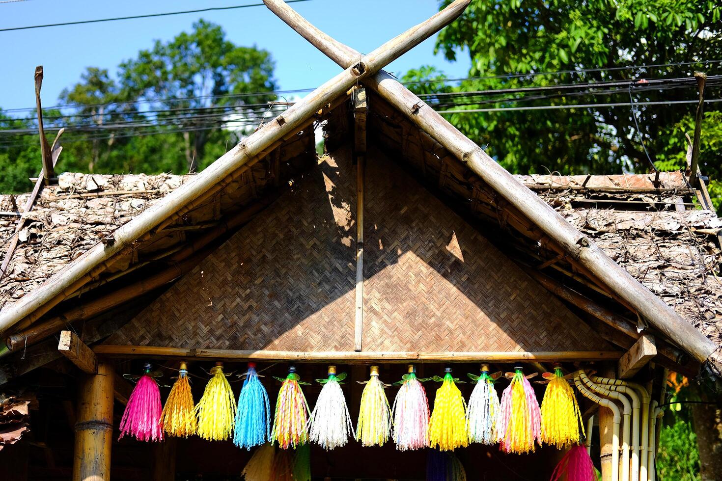 entrance decoration colorful tassels with wooden sculpture decorated on the roof of tradition house lanna style in northern of Thailand photo