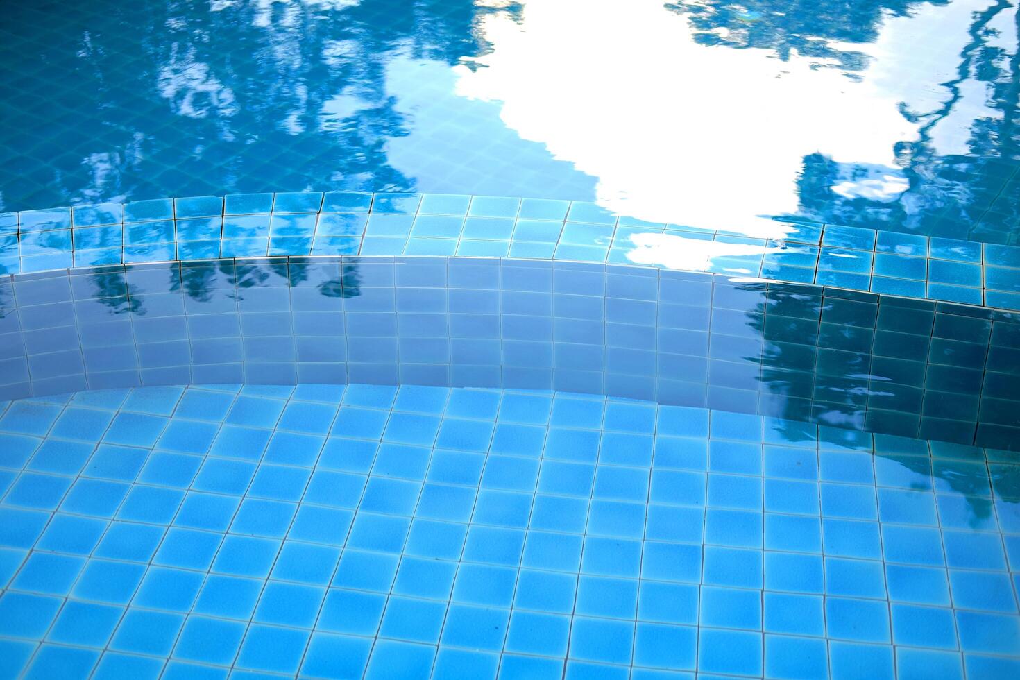 Blue water and ceramic tiles in swimming pool outdoor in garden of resort and hotel photo