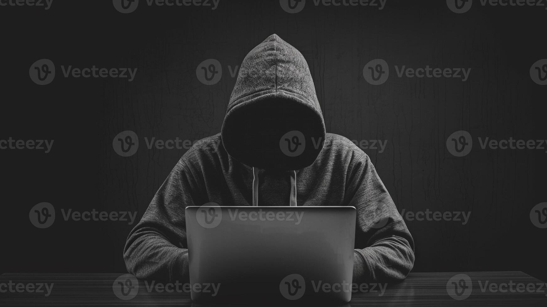anonymous hacker in hoodie with no face using laptop computer on dark background. thief get into internet system. cyber crime and digital fraud prevention photo