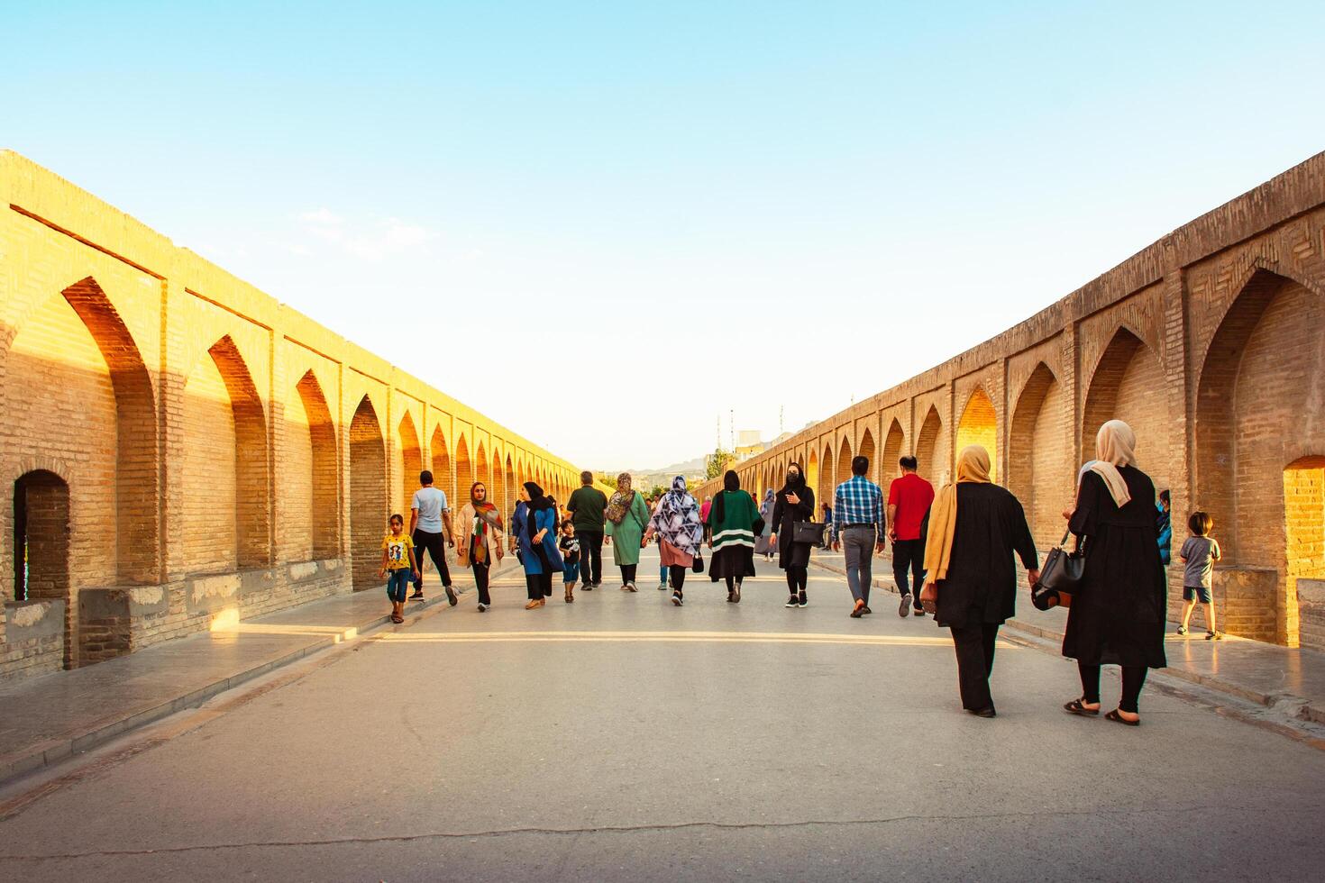 Isfahan, Iran - May 2022 -people walk on Sio Se Pol or Bridge of 33 arches, one of the oldest bridges of Esfahan and longest bridge on Zayandeh River photo