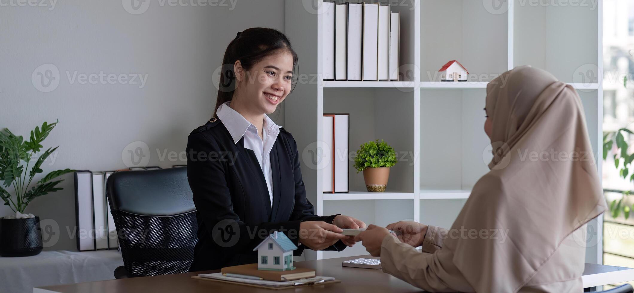 A real estate agent offers a house to a female Muslim client. The concept of buying and selling houses and real estate. photo
