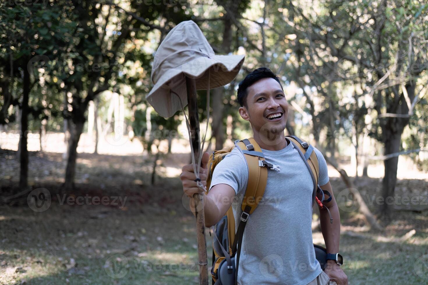 Portrait of a happy smiling Asian tourist, 30-35 years old, backpacking in a national park. asian male tourist enjoying his hiking trip Nature activities, holidays, outdoor hobbies. photo