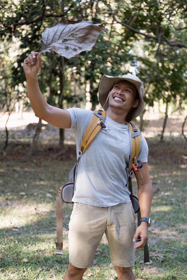 Portrait of a happy smiling Asian tourist, 30-35 years old, backpacking in a national park. asian male tourist enjoying his hiking trip Nature activities, holidays, outdoor hobbies. photo