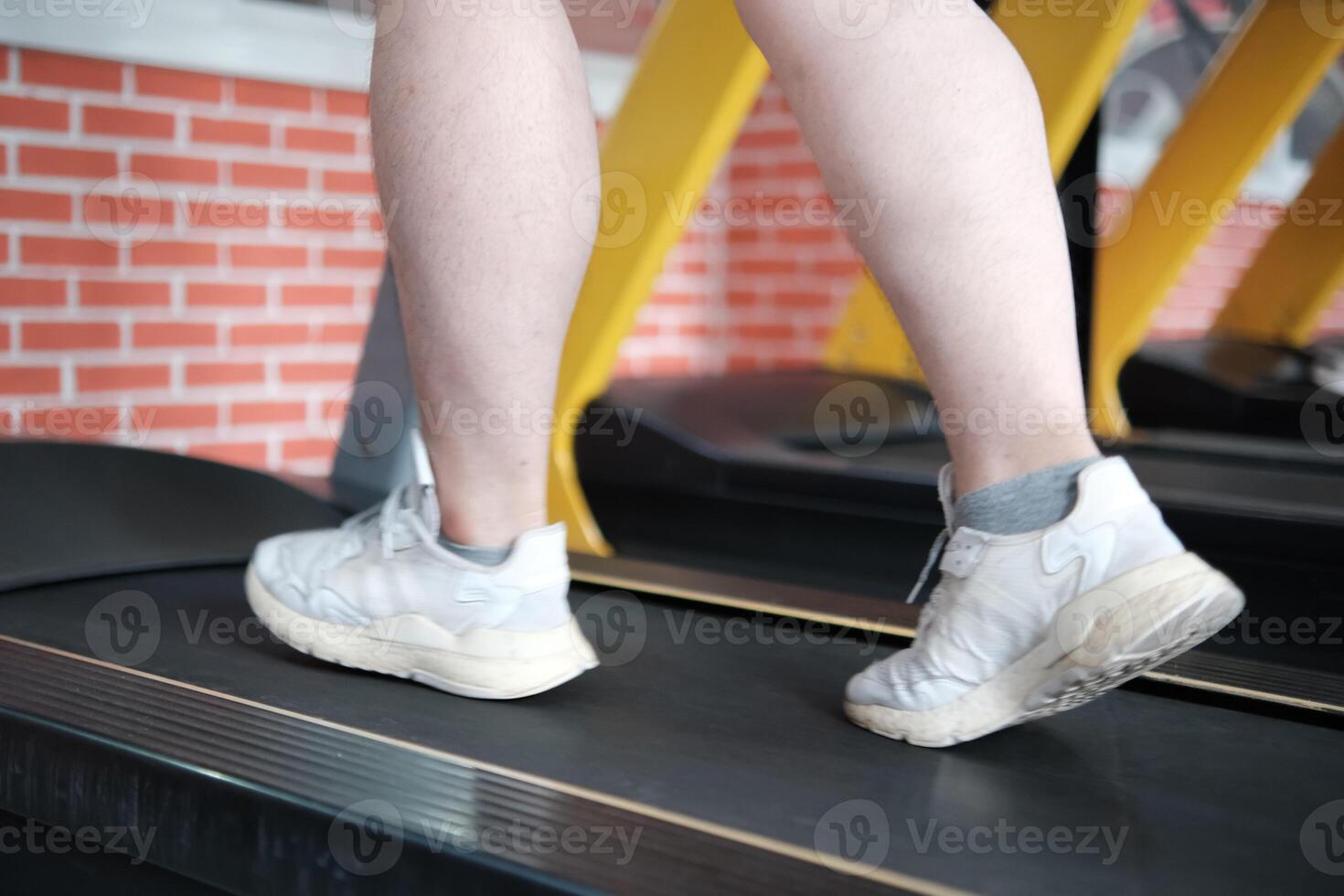 Close-up shot of an overweight man's legs walking on a treadmill in the gym. photo