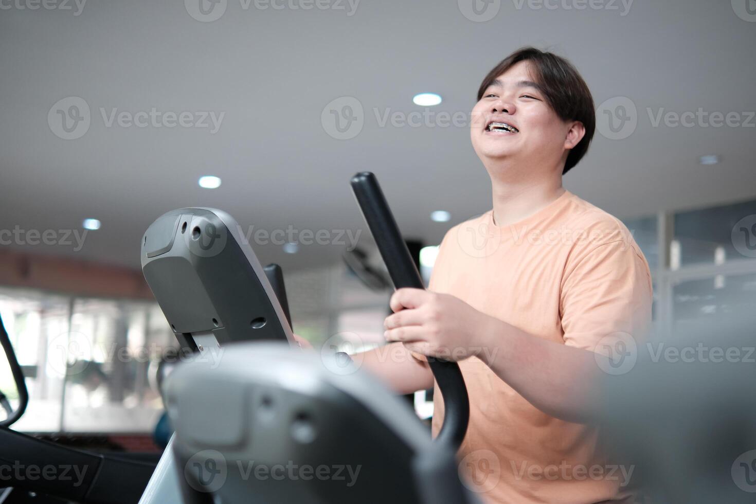 Overweight man smiling while exercising on elliptical photo