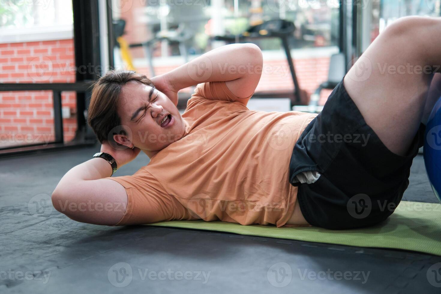 Overweight man doing crunches on exercise mat photo