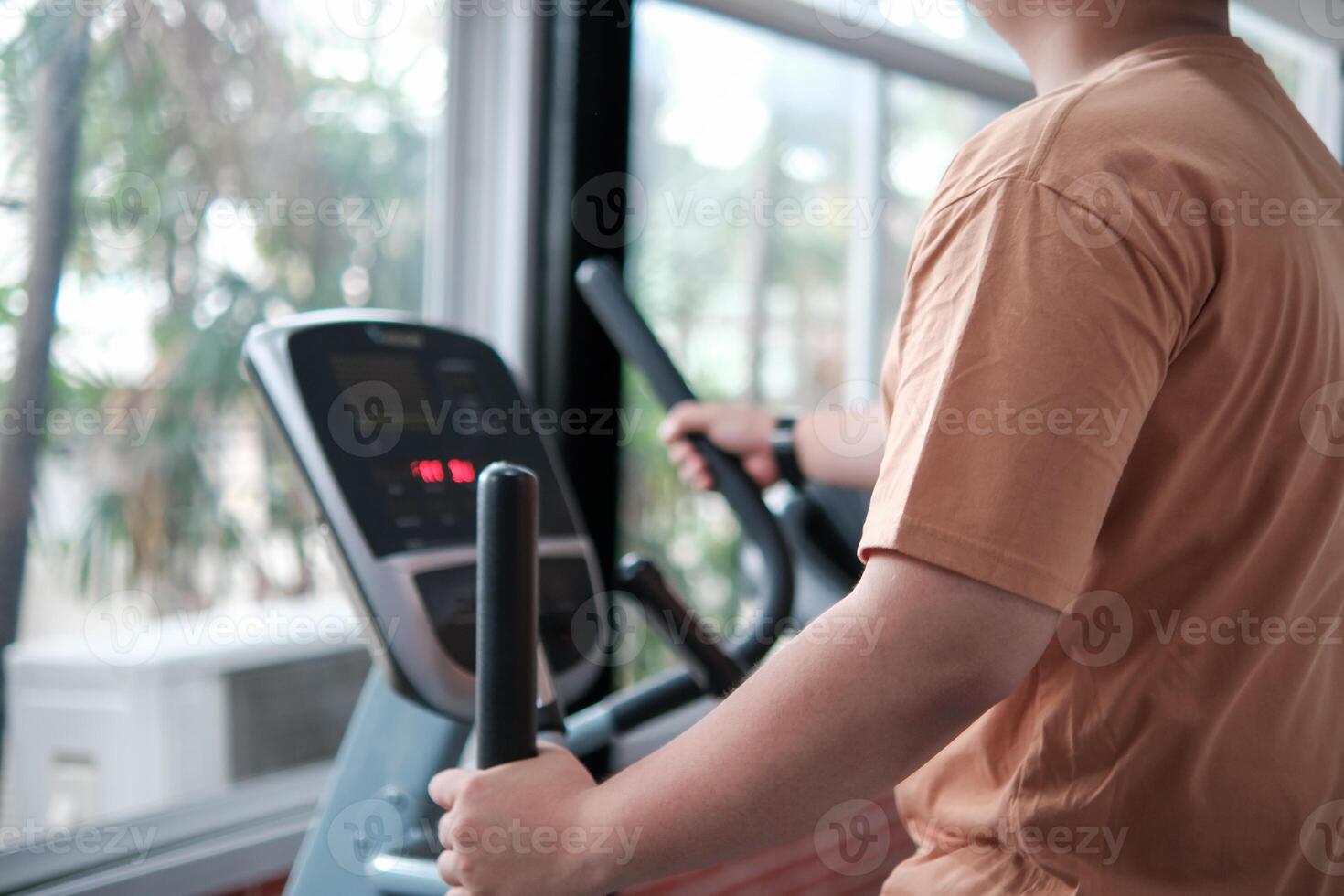 Overweight man exercising on an elliptical machine in the gym photo