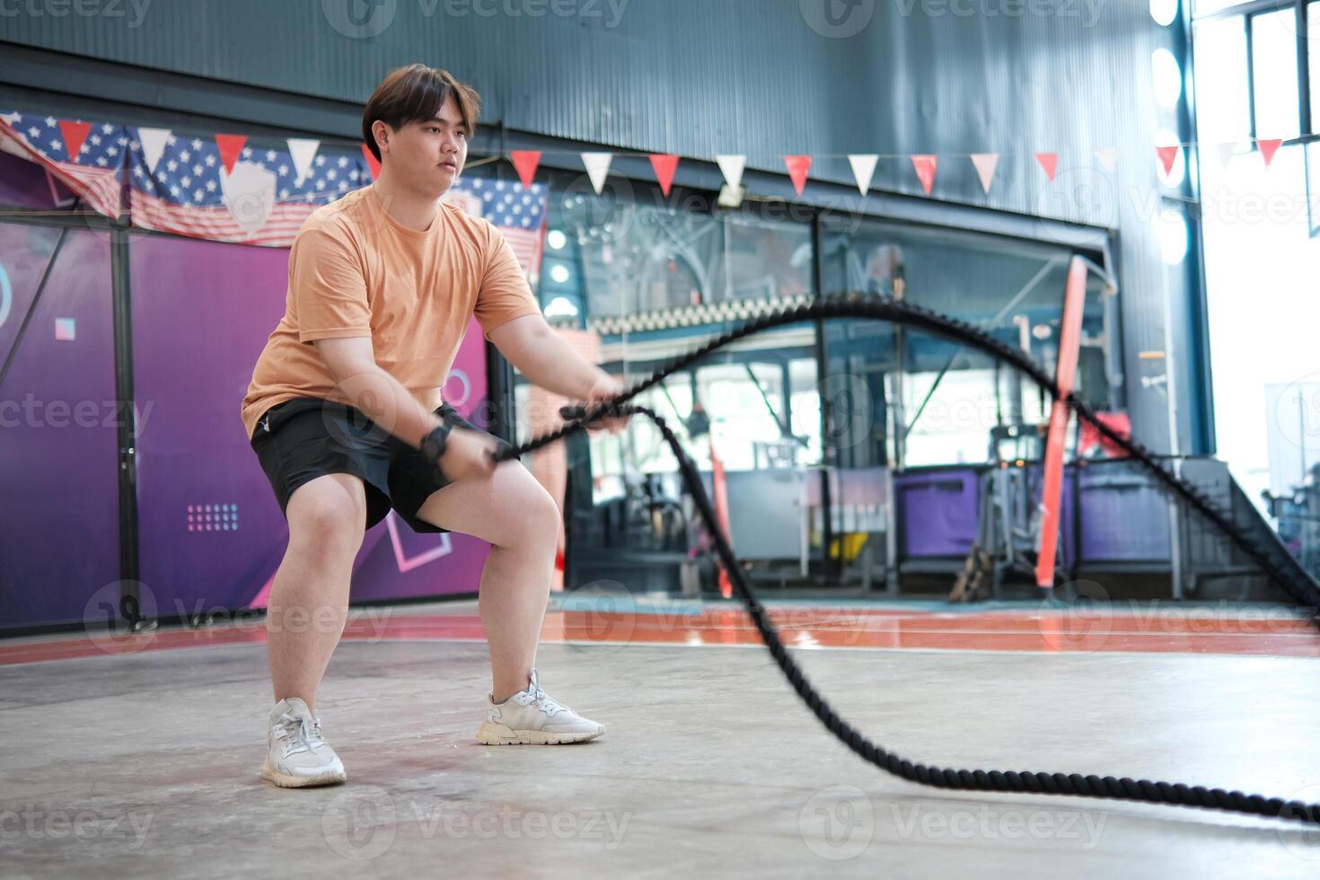 An overweight man is holding a rope and appears to be exercising photo