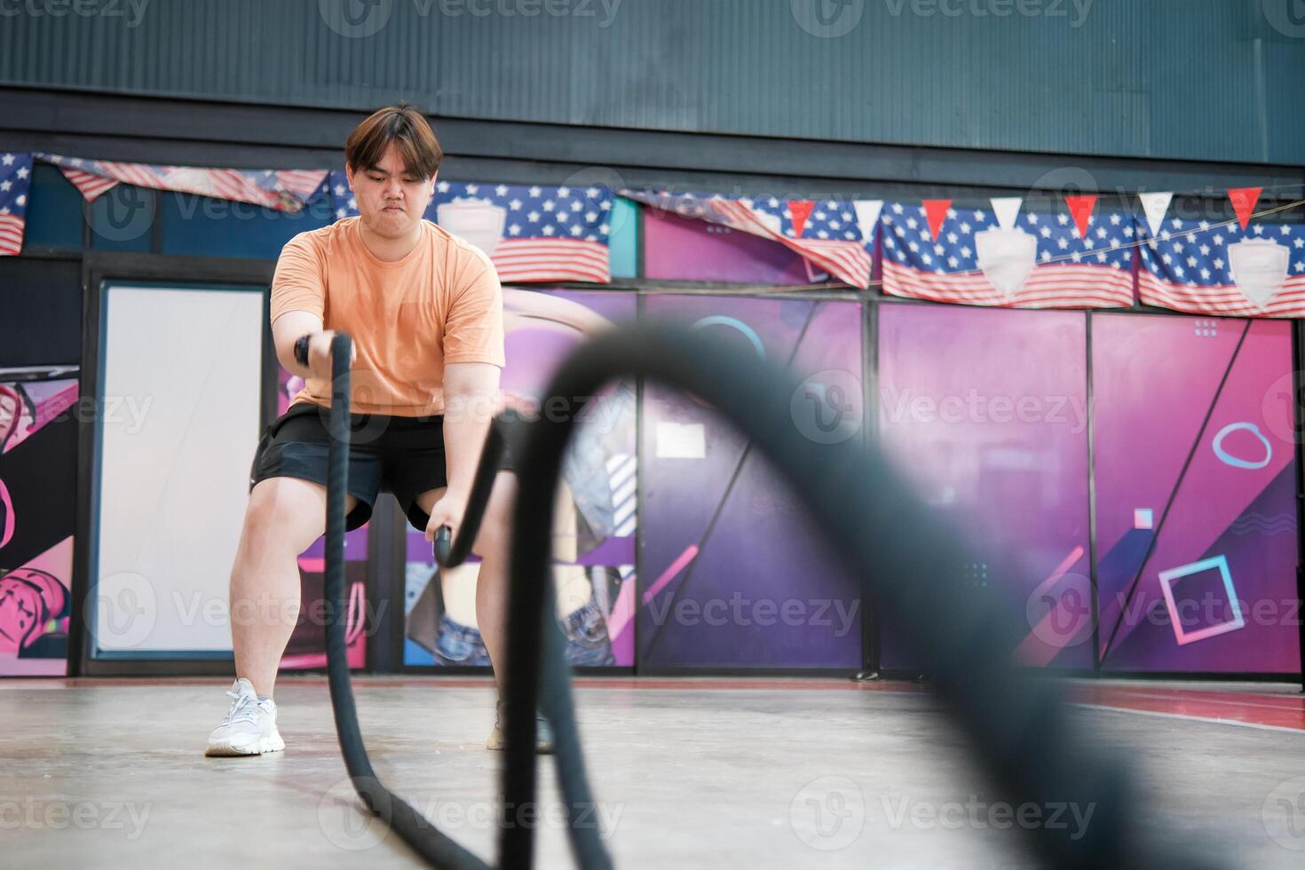 An overweight man is holding a rope and appears to be exercising photo