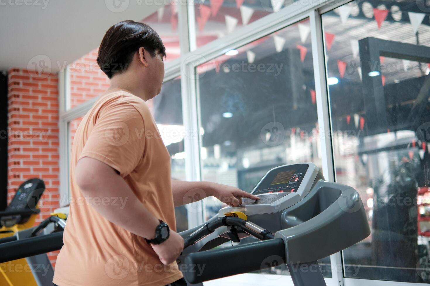Overweight man running on treadmill in gym photo