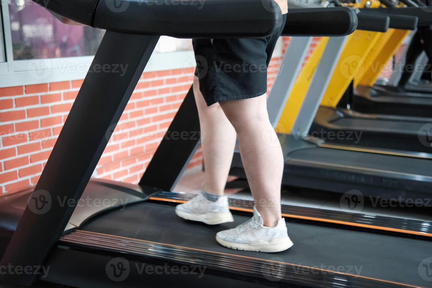 Close-up shot of an overweight man's legs walking on a treadmill in the gym. photo