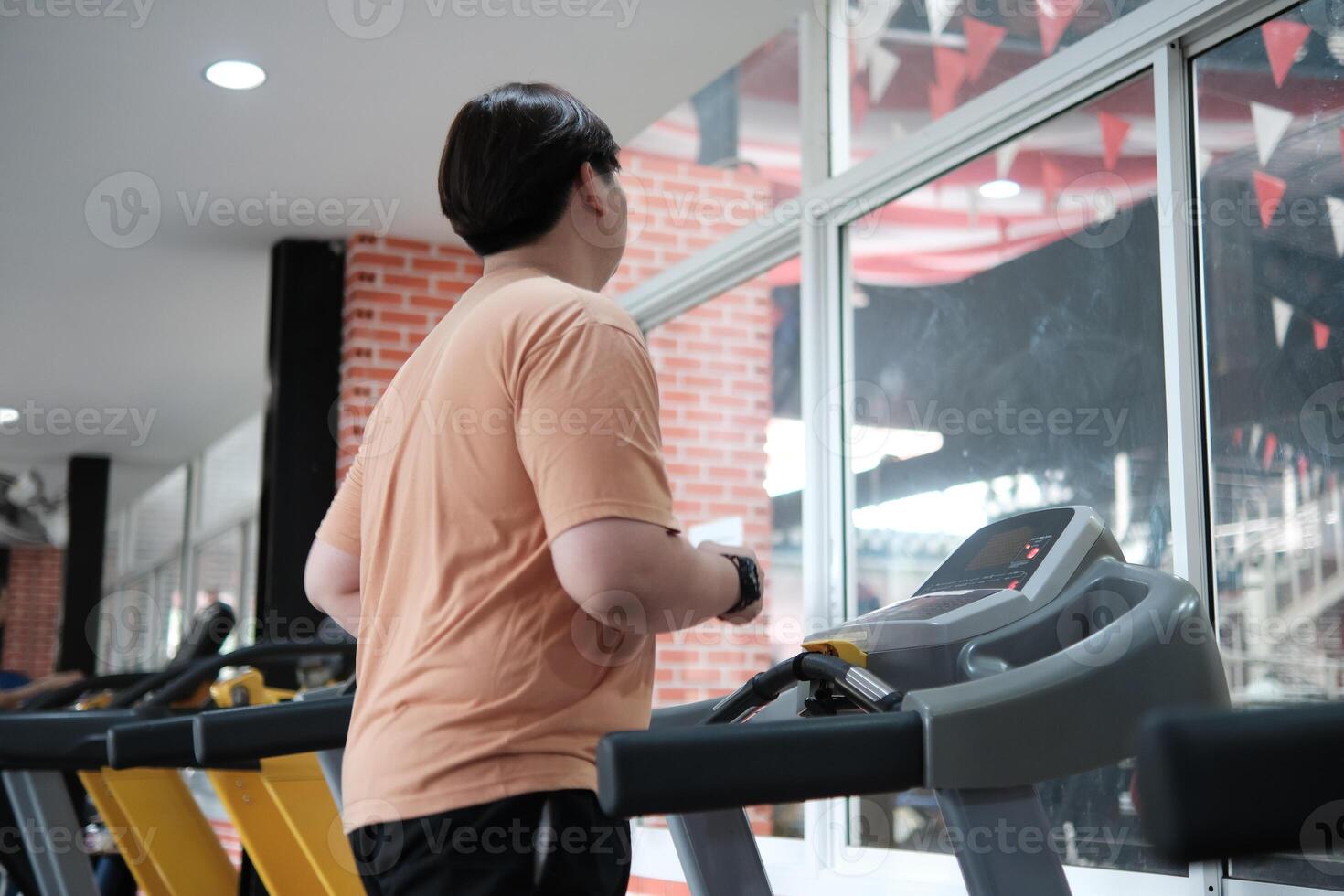 Overweight man running on treadmill in gym photo