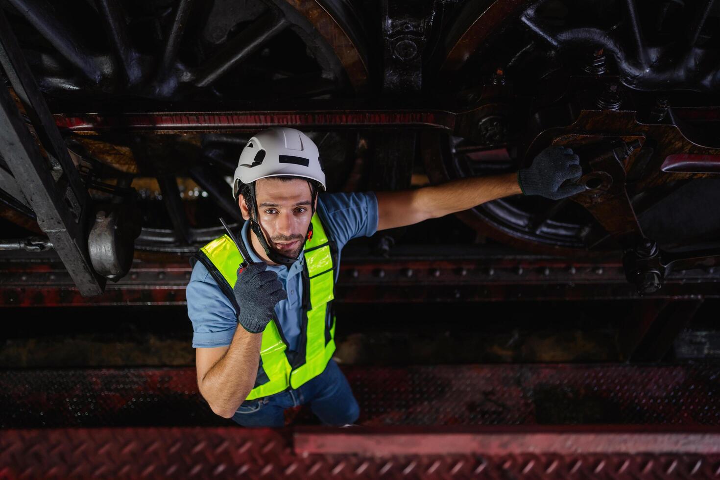 man in a yellow vest is standing on a platform, looking down at a train photo