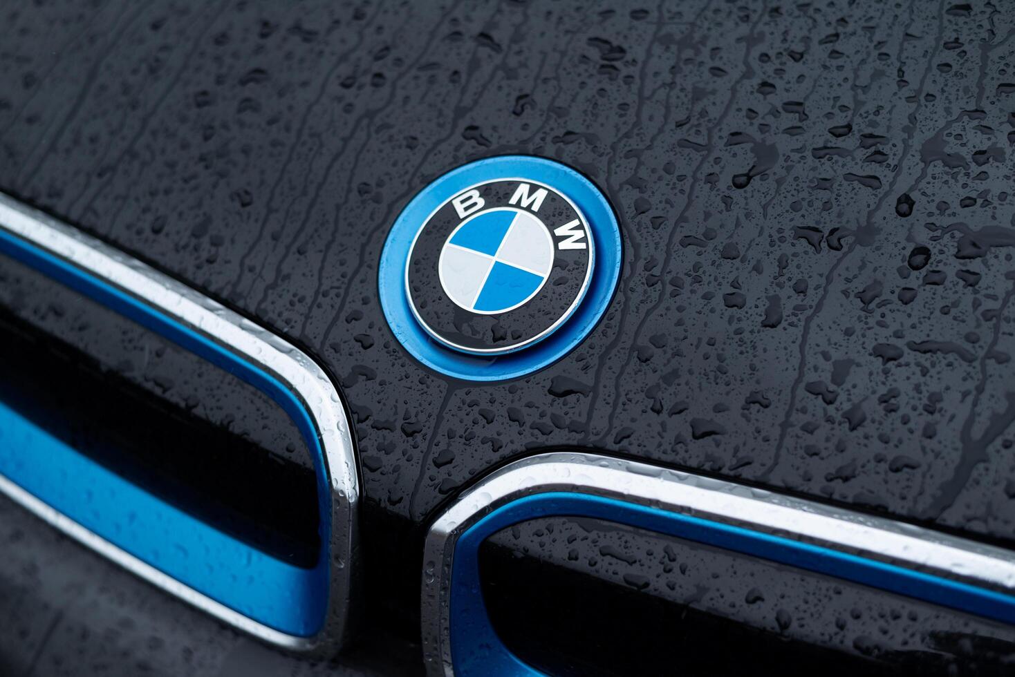 Kyiv, Ukraine - June 12, 2024. Emblem of BMW i in blue edging on hood of electric car model i3 with rain drops photo