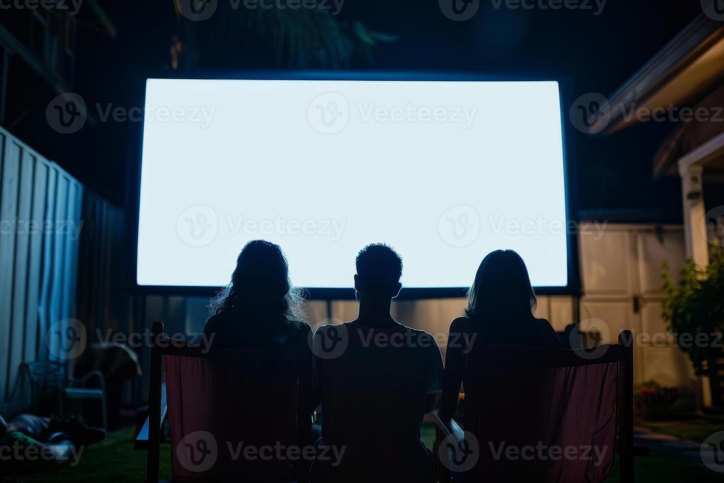 Three people are sitting in lawn chairs in front of a large screen photo