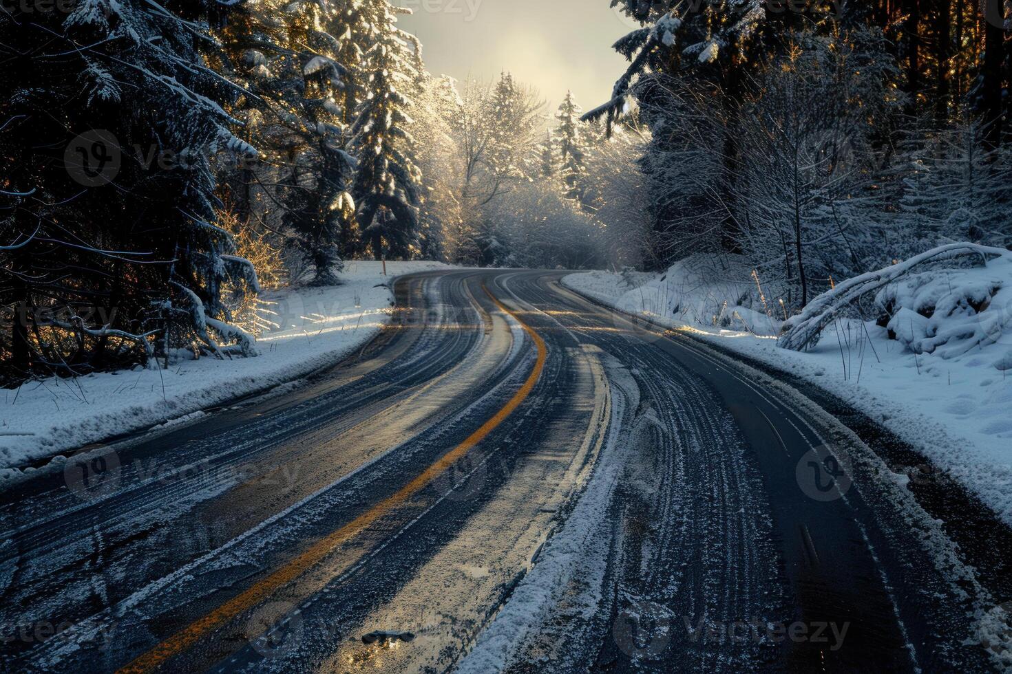 Curvy road with tire tracks through a snowy forest during a tranquil sunset photo