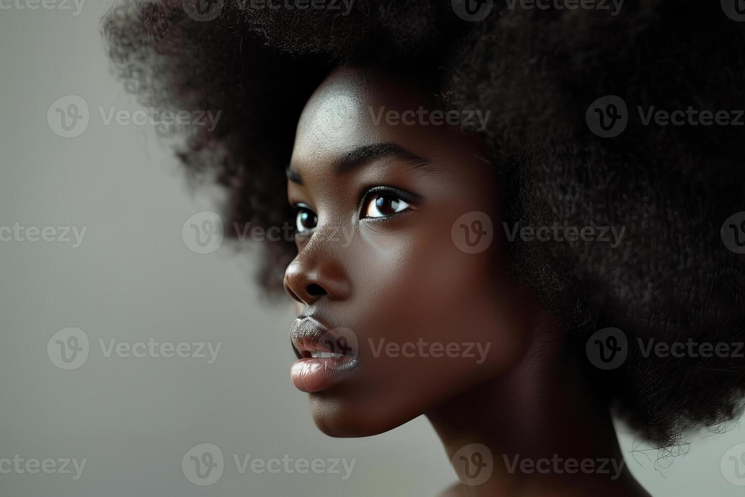 Young black woman with afro hairstyle posing on gray background photo